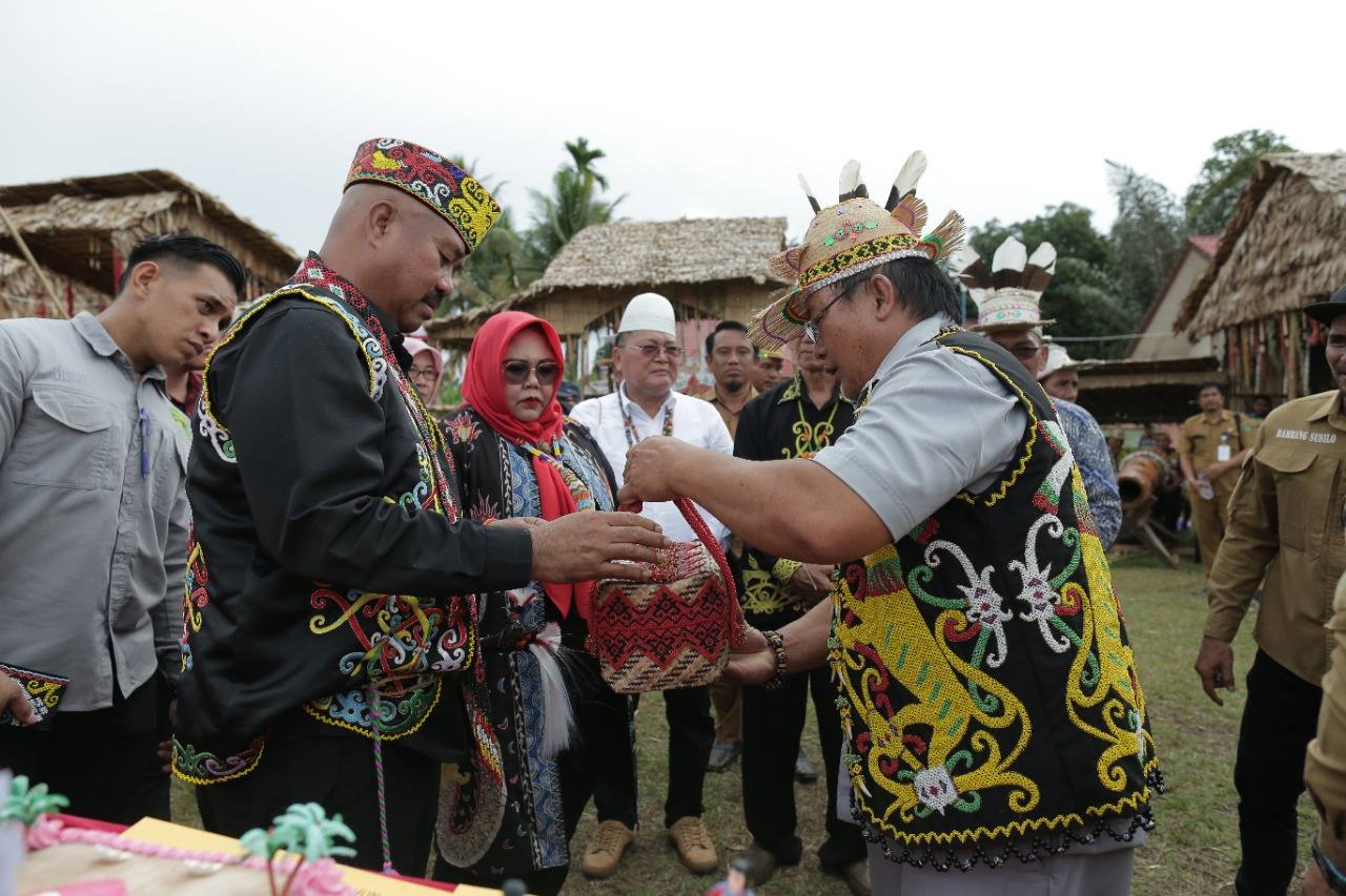 Bupati Kutai Kartanegara Edi Damansyah dihadiahi cinderamata oleh Kepalat Adat Desa Buluq Sen, Kurlin Lawai.